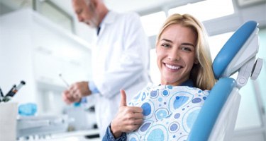 smiling woman giving a thumbs up at her dental checkup in Guilderland 