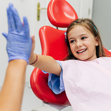 Child giving dentist a high five and dental checkup visit