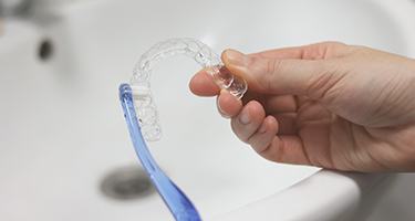Patient using toothbrush to clean aligners