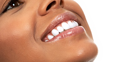 profile view of a woman tilting her head up and smiling to show off her bright white teeth