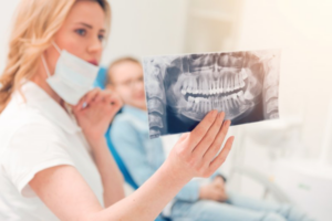 Dentist looking at her patient’s X-ray while he watches in the background